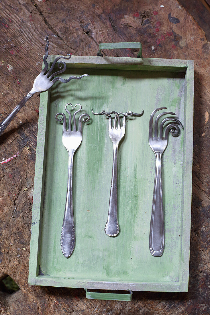 Artfully bent forks on wooden tray