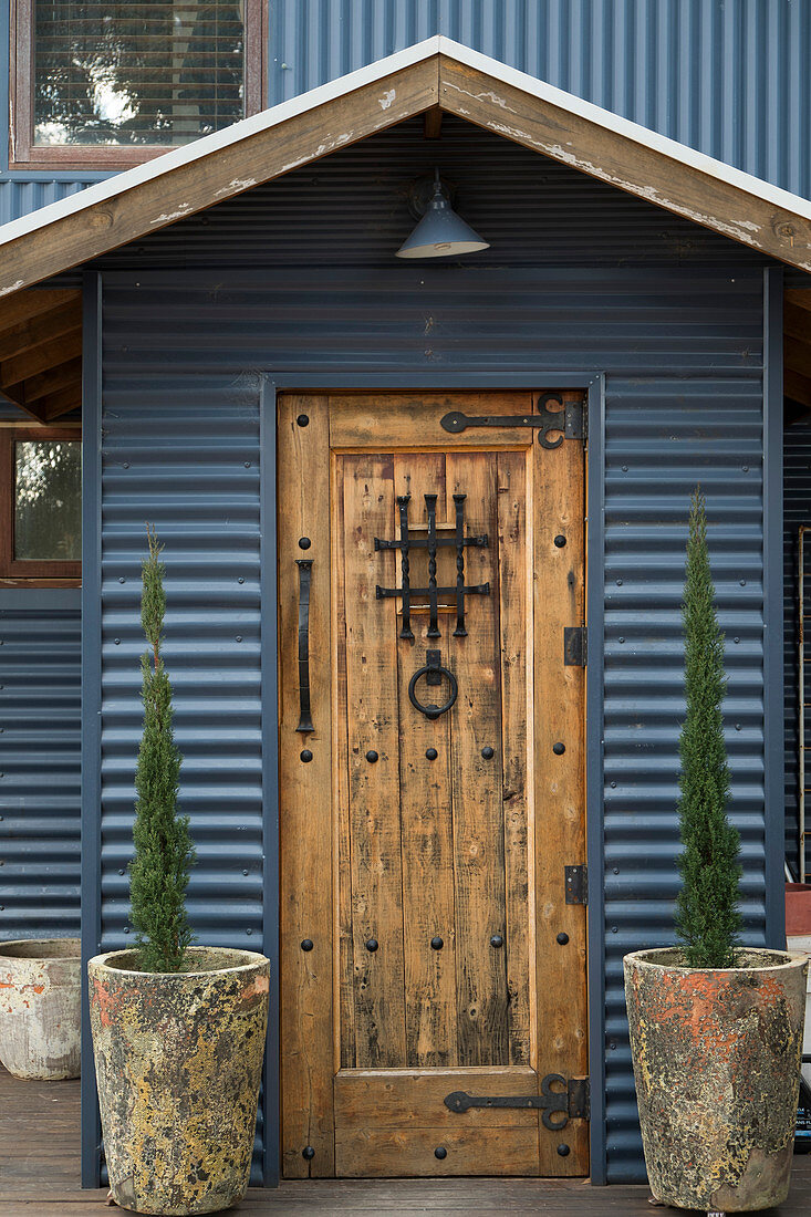 Rustic wooden door with metal fittings in corrugated metal wall of house