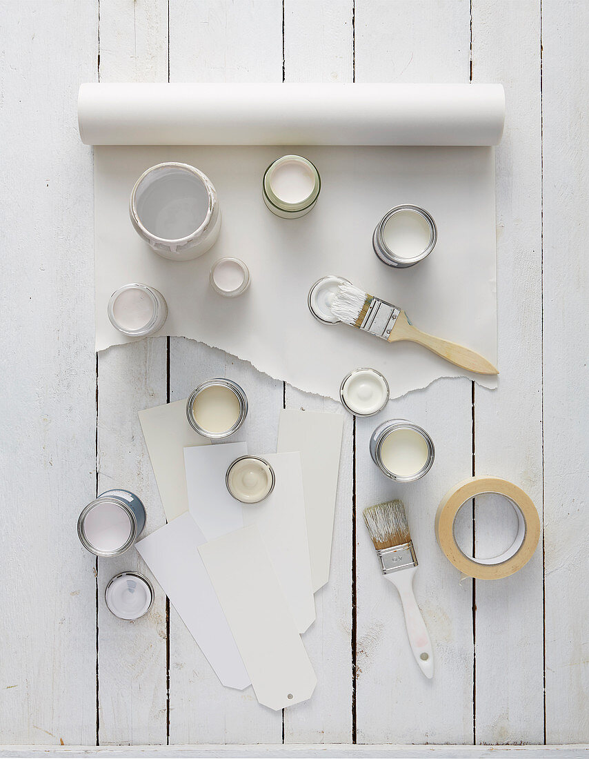 Open pots of paint in various shades of white on roll of paper