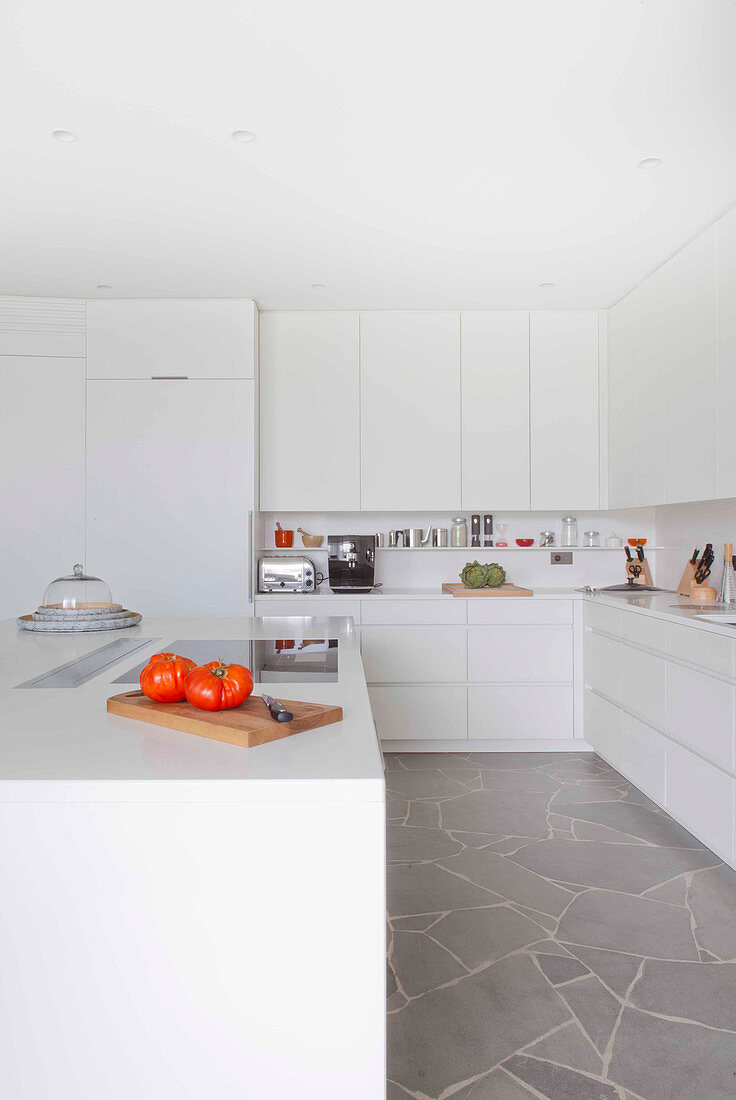 weiße Einbauküche mit Kücheninsel und Steinplatten
