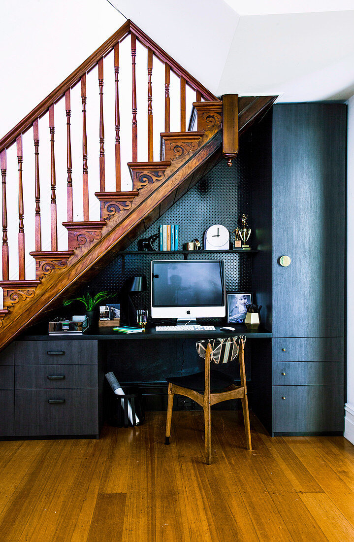 Home office with black accessories under the stairs