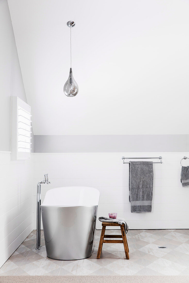 Frei stehende Badewanne in weißem Badezimmer im Dachgeschoss