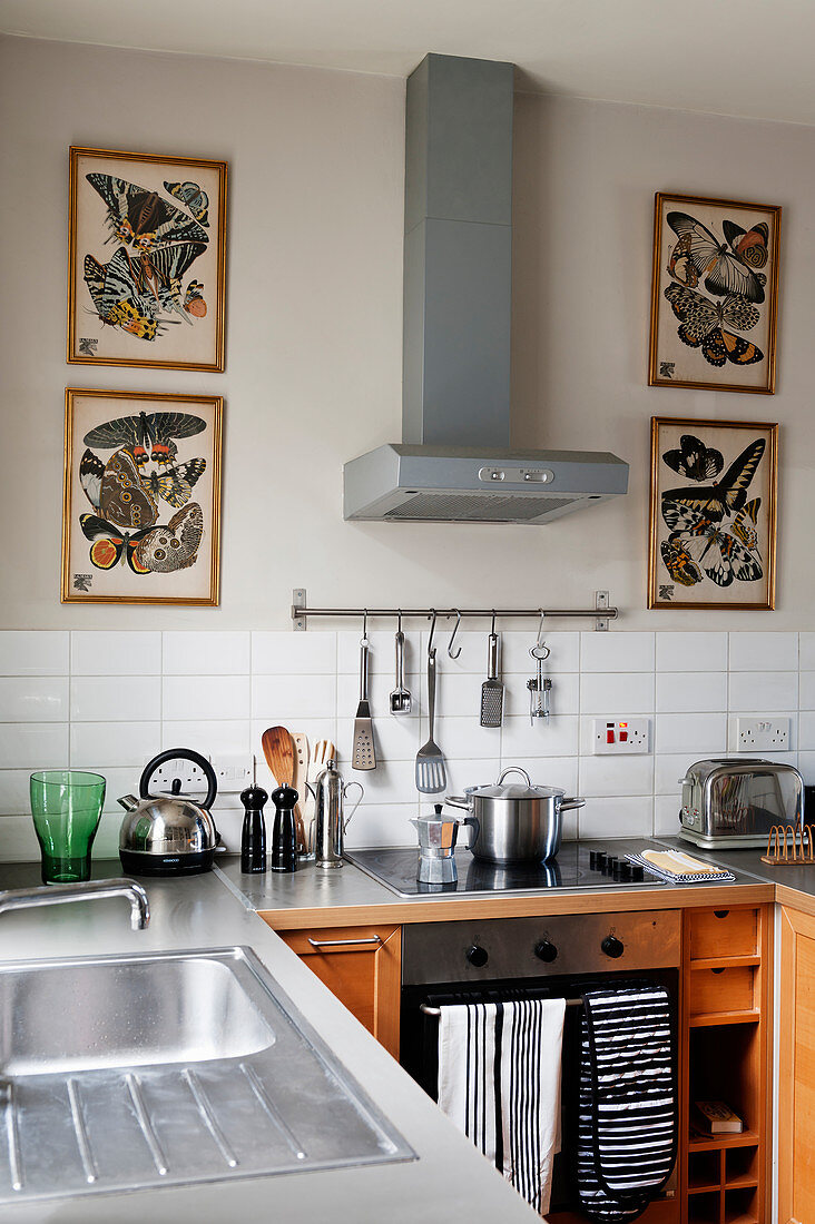 Four pictures of butterflies flanking extractor hood in kitchen