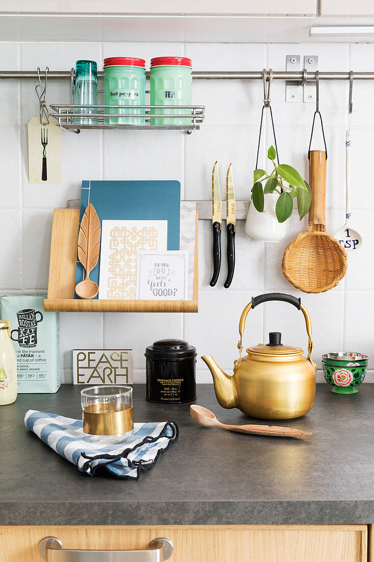 Book stand and various utensils hung above gold kettle on kitchen worksurface