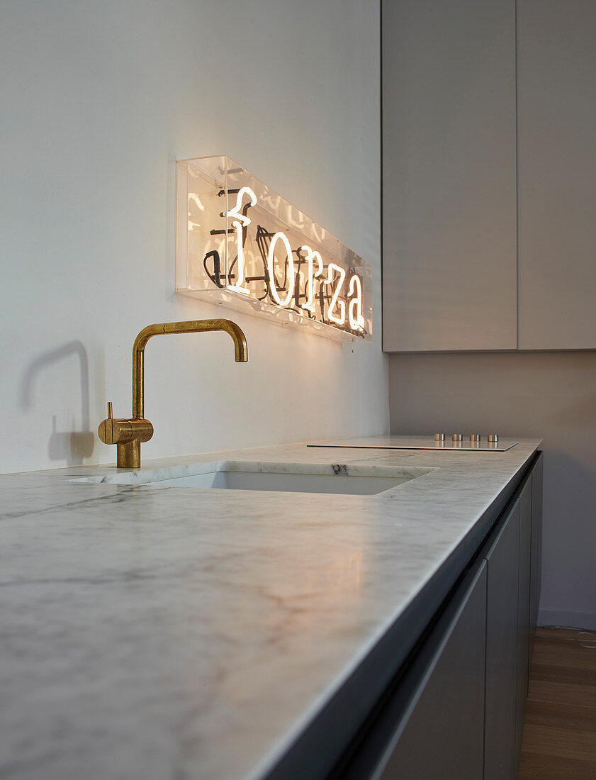 Illuminated lettering above sink in minimalist kitchen