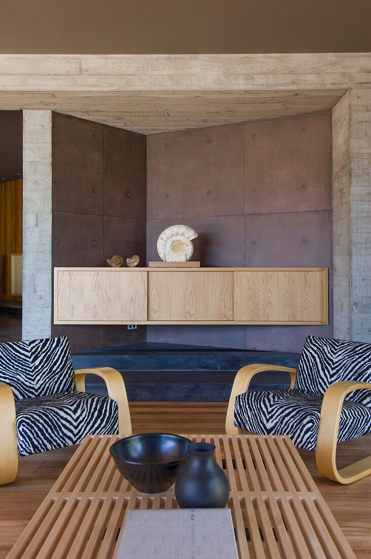 Zebra-patterned armchairs in living room with concrete walls