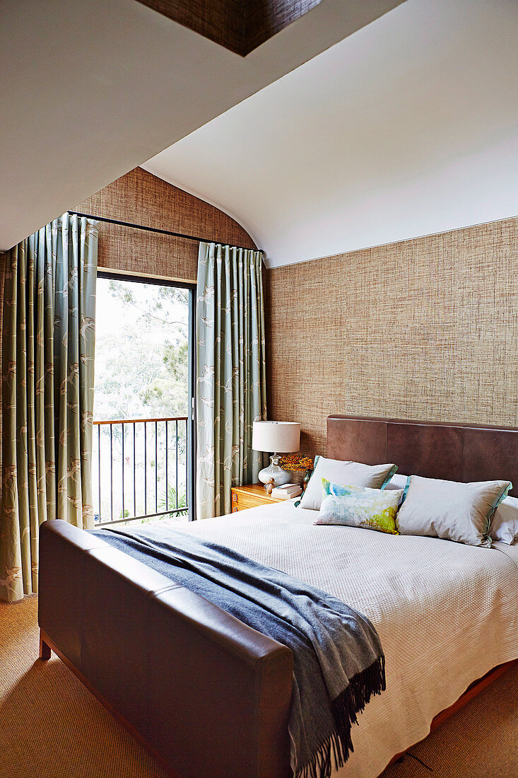 Doppelbett mit Leder Kopf- und Fußteil, Textiltapete und französisches Fenster im Schlafzimmer
