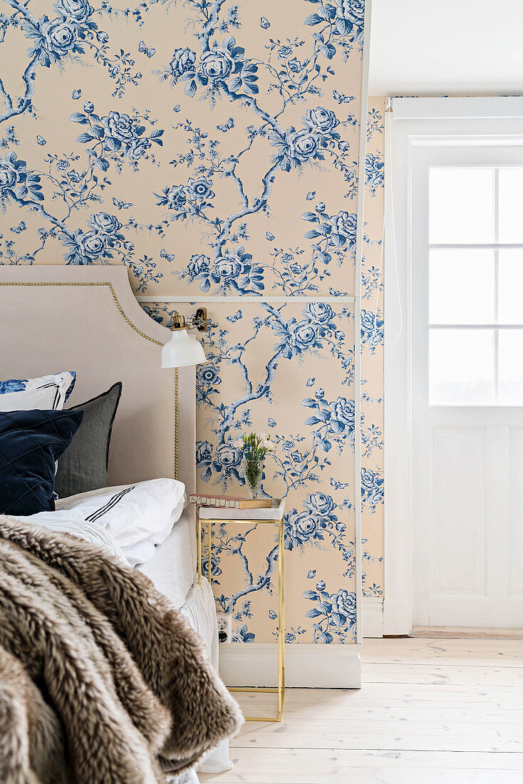 Doppelbett mit Betthaupt, Wandlampe und Nachttisch in romantischem Schlafzimmer mit floraler Tapete