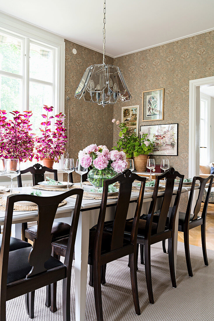 Set table and old chairs in dining room with vintage-style wallpaper