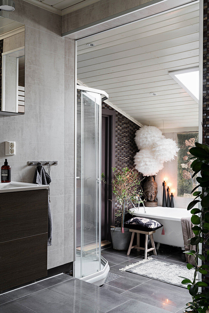 Grey bathroom on two levels with bathtub under sloping ceiling