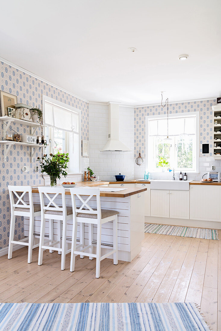 Helle, offene Küche mit Frühstückstheke, Teppichläufer und Tapete in Blautönen