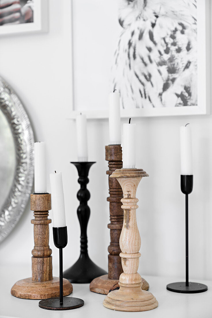 White candles in various wood and metal candlesticks