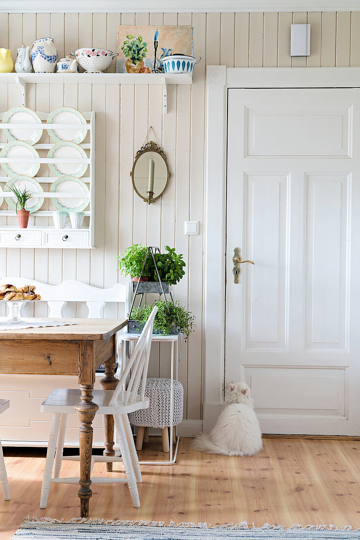Rustikaler Tisch vor Tellerboard in Wohnküche mit weißer Tür und Holzverkleidung