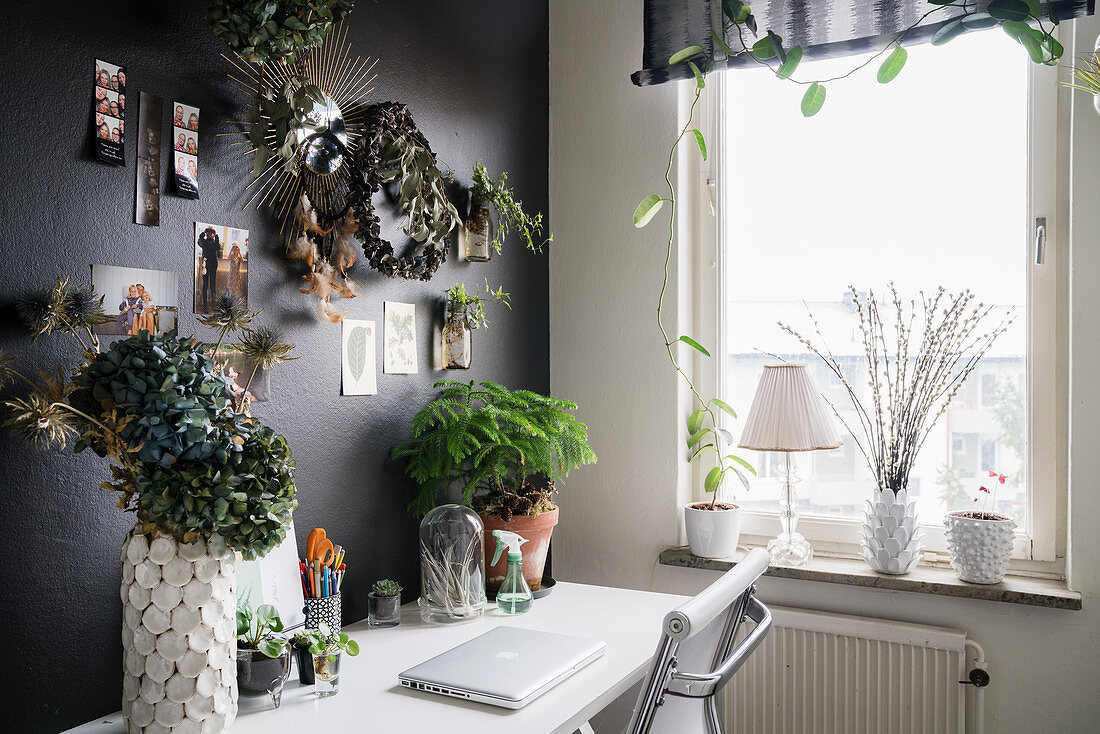 Schreibtisch an schwarzer Wand mit Pflanzen