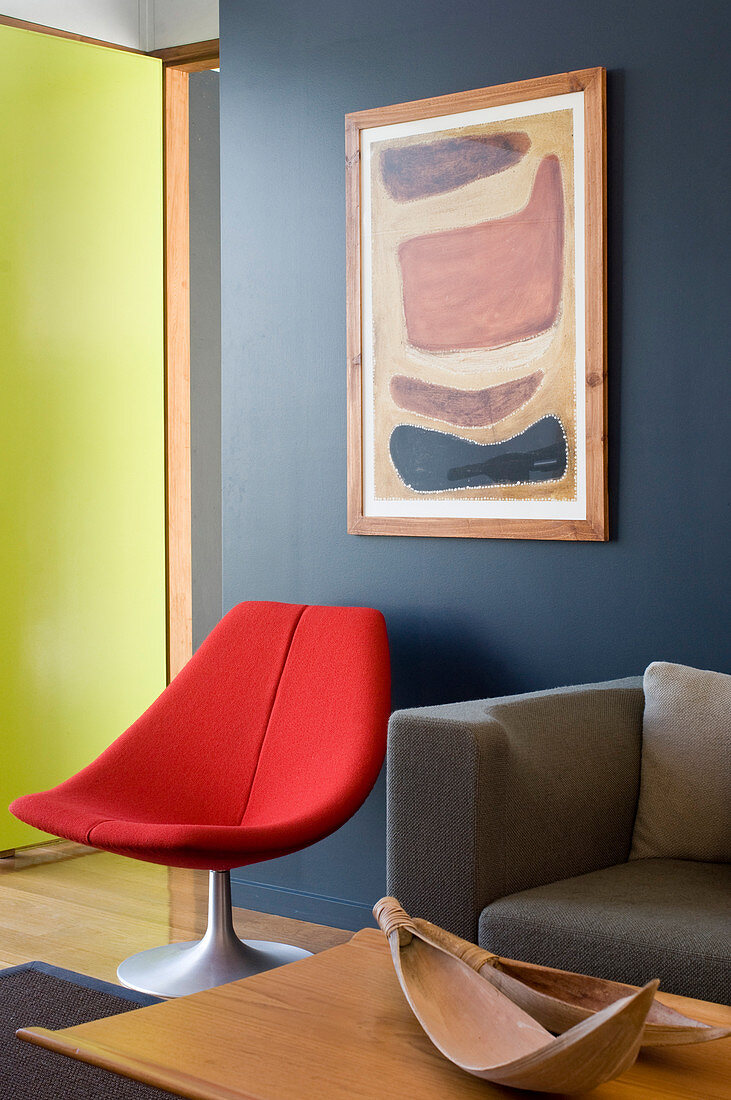 Red chair below painting on grey wall