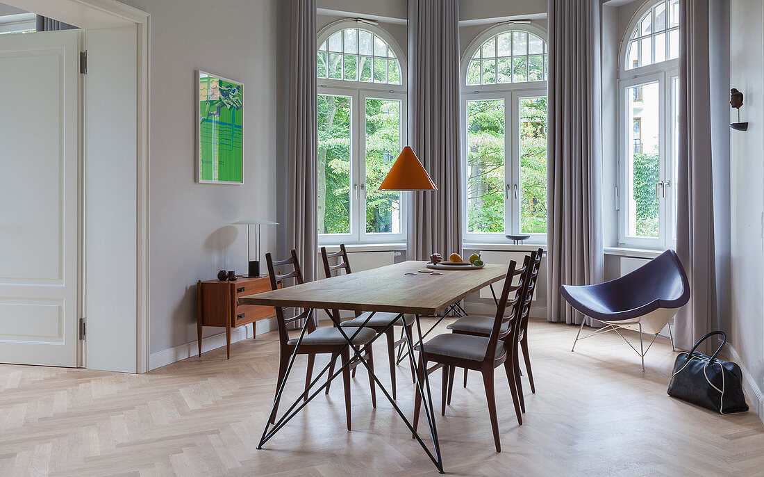Dining table with slender lines and designer chairs in window bay