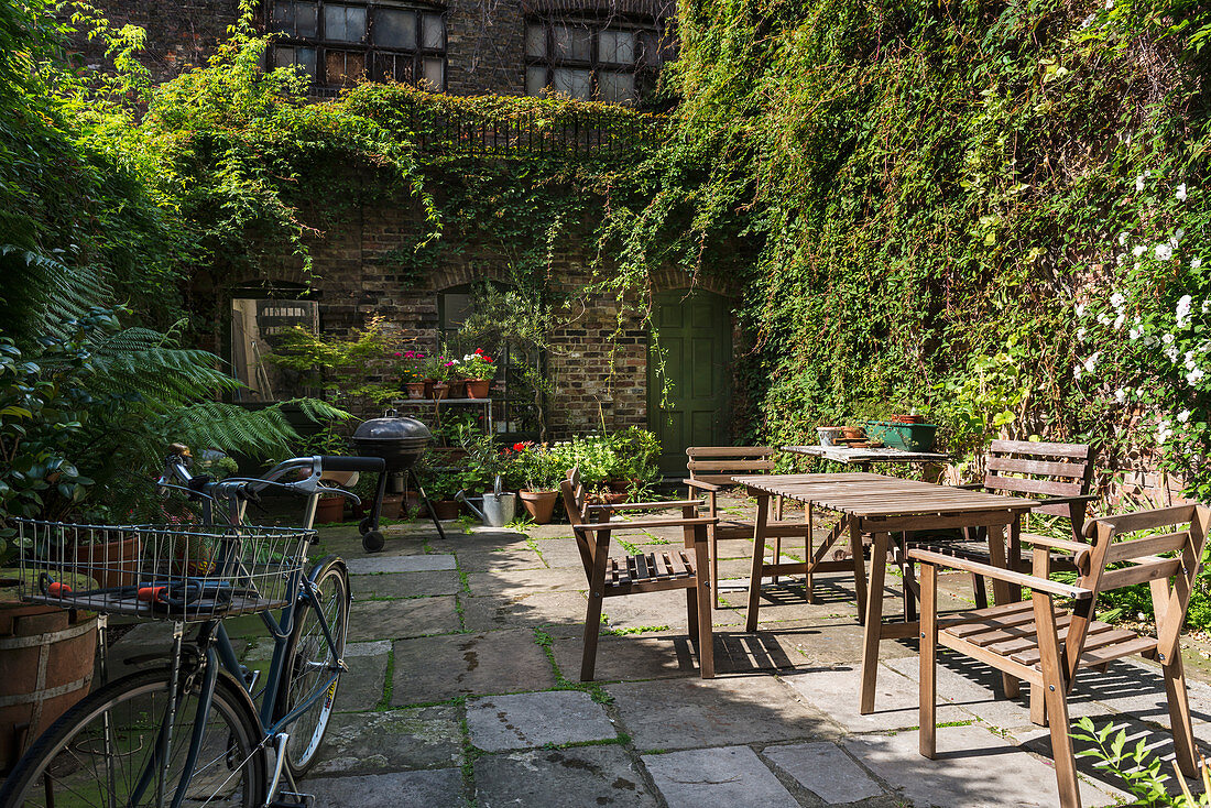 Table and chairs in planted courtyard of old English townhouse