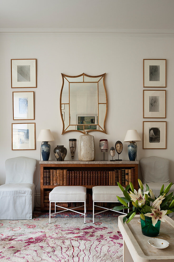 Bücherregal darüber Spiegel eingerahmt von Wandbildern in elegantem Wohnzimmer