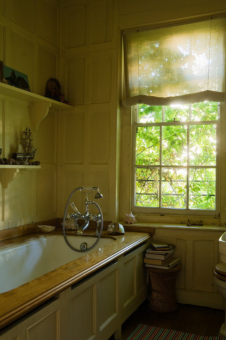 Antike Badewanne mit Holzeinfassung und Holzvertäfelung in Bad mit Sprossenfenster