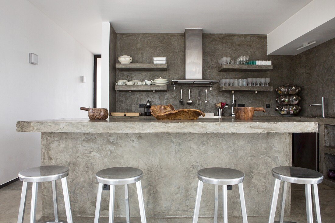 Cast concrete kitchen counter and silver bar stools in open-plan kitchen