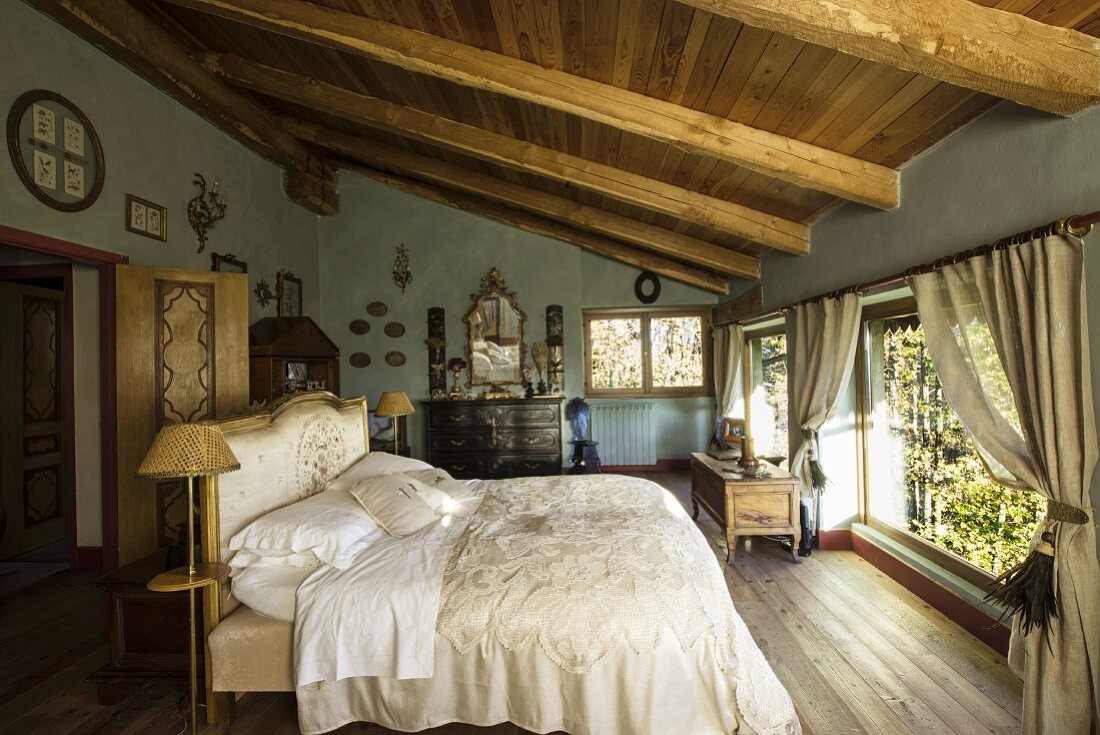 Dachgeschossschlafzimmer im Landhausstil mit edler, nostaglischer Bettwäsche und Antikmöbeln