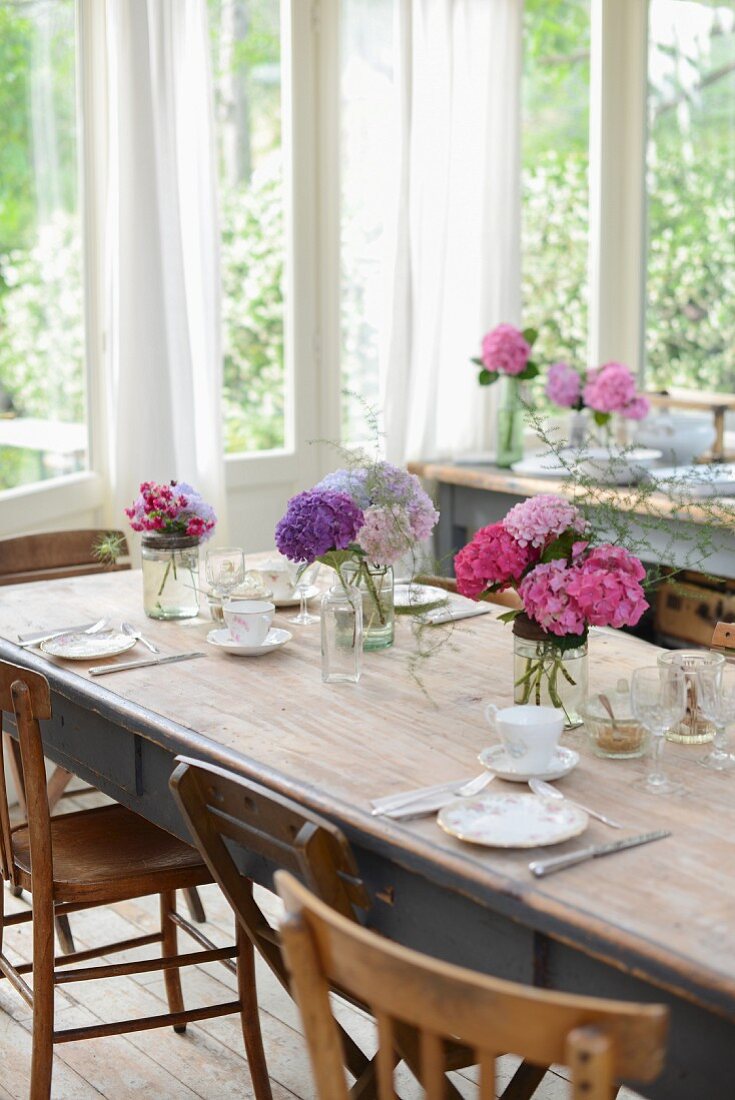 Set table with several vases of hydrangeas in conservatory
