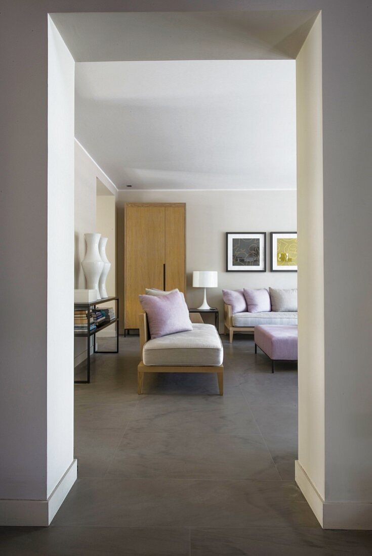 Blick in eleganten Loungebereich mit pastellfarbenen Kissen und Polstertisch