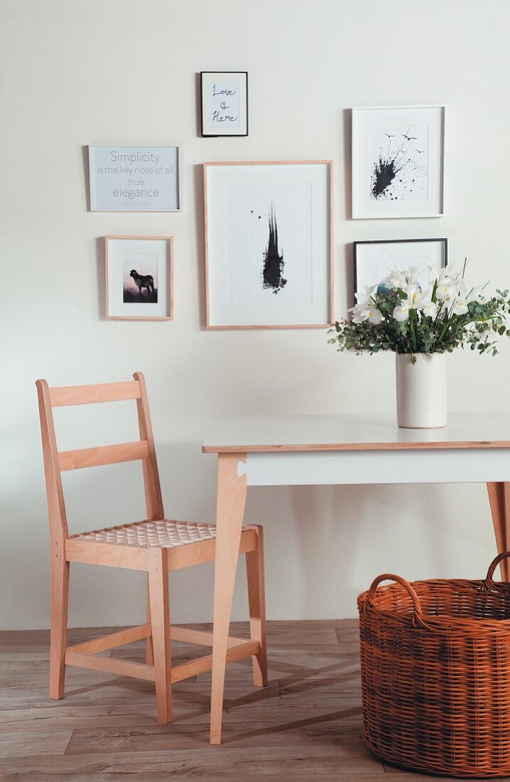 Bilderwand über einem Stuhl und Tisch mit Blumenstrauß