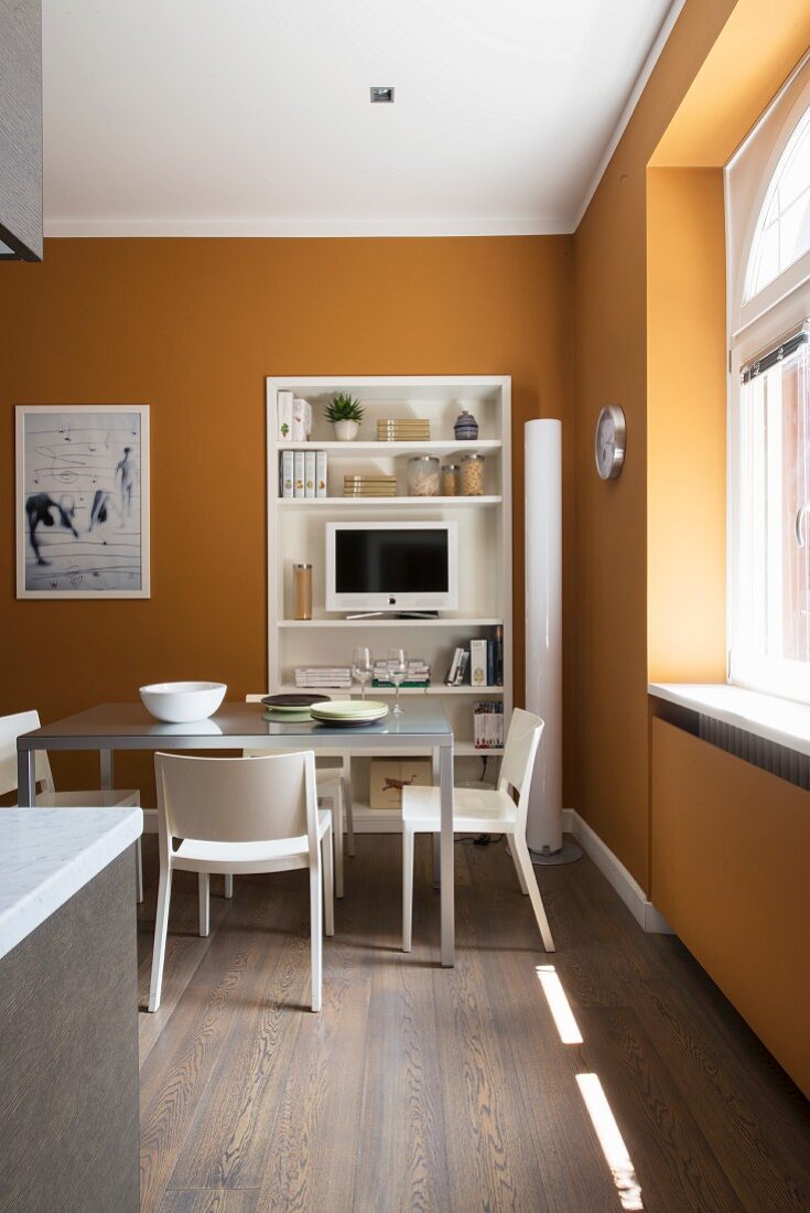 Moderner Esstisch vor einem Regal in der Küche mit gelben Wänden