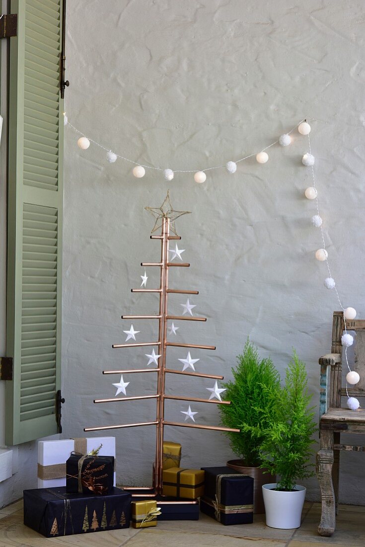 Presents below stylised Christmas tree made from copper piping and decorated with paper stars