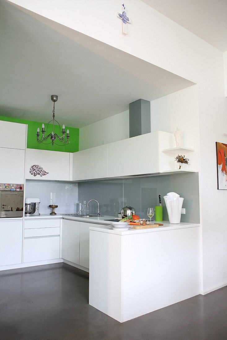 Blick in offene Küche mit weißen Fronten und grauem Spritzschutz
