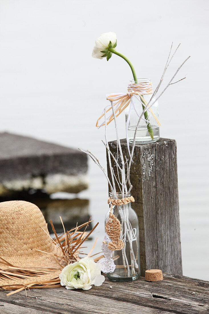Hand-made straw hat and glass bottle decorated with raffia