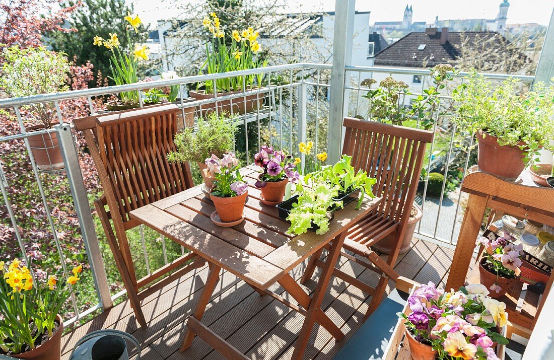 Balkon mit Holzmöbeln und Frühlingsblumen