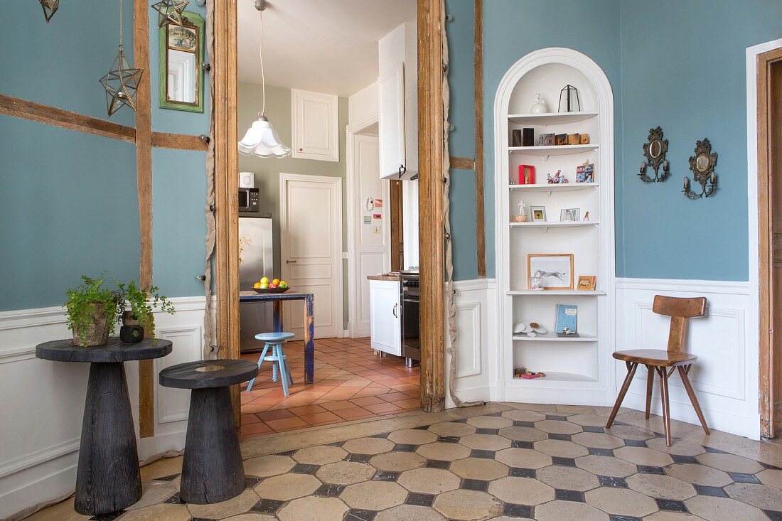 Blick vom Vorraum mit Einbauregal und blauen Wänden in die Küche