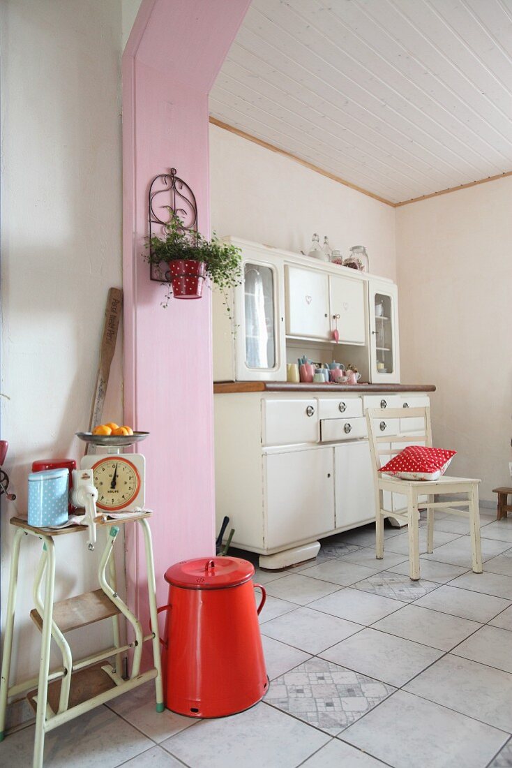 Küchenecke mit 50er-Jahre Anrichte, davor rosafarbene Holzverkleidung