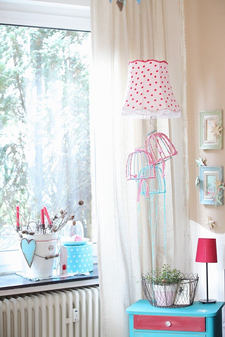 Corner room romantically decorated with red and white lampshades and pastel picture frames