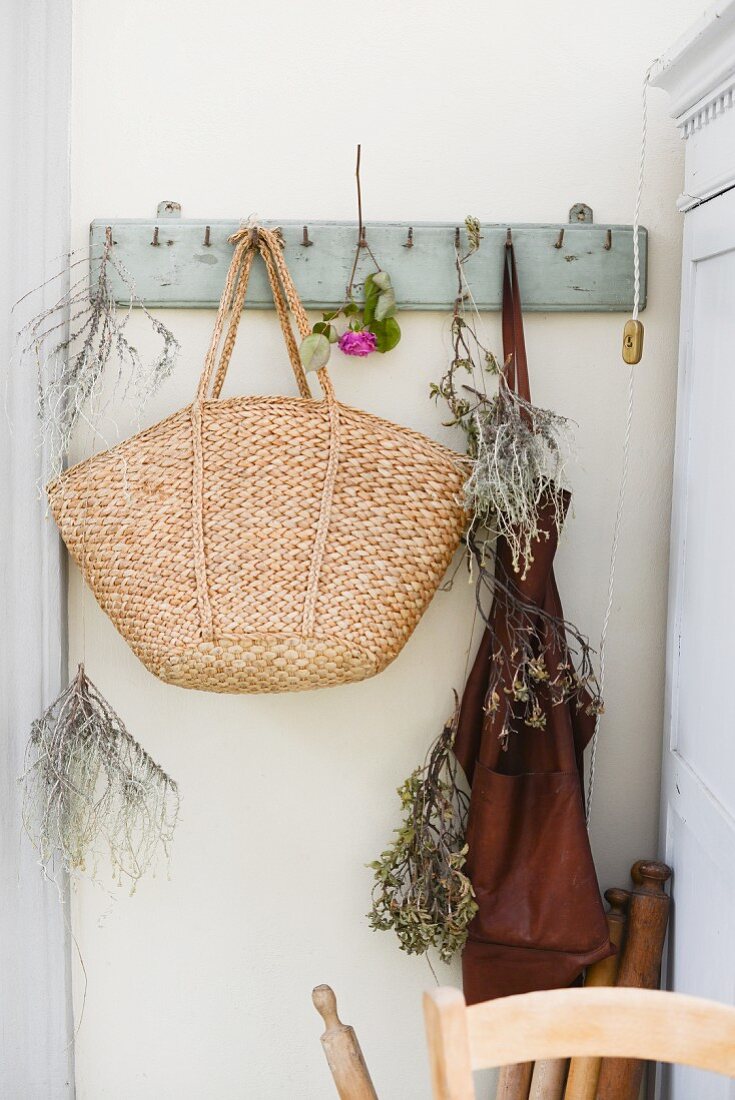 Raffia shopping bag, dried herbs and apron hanging from coat pegs