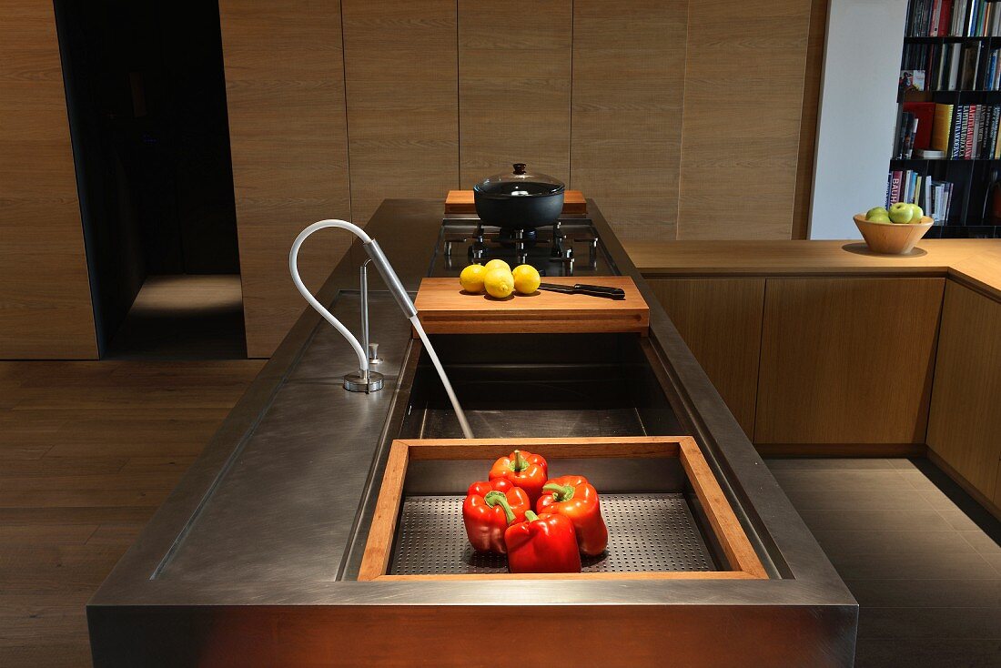 Moderne Küchentheke aus Metall mit integriertem Holzschneidebrett und Gasherd vor schlichter Schrankwand
