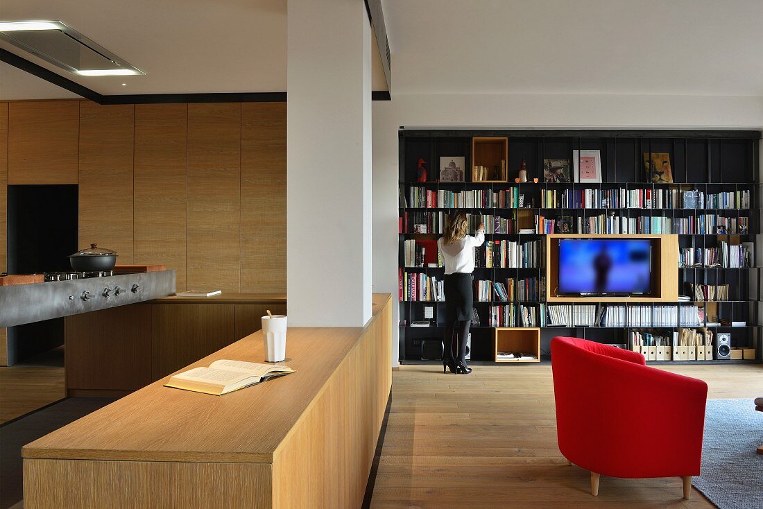 Offenes Wohnen mit moderner Holzküche und schwarzem Metall-Bücherregal mit integiertem Fernseher