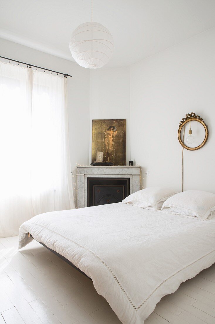 Schlafzimmer in Weiß mit Kamin in der Ecke und schwebendem Bett