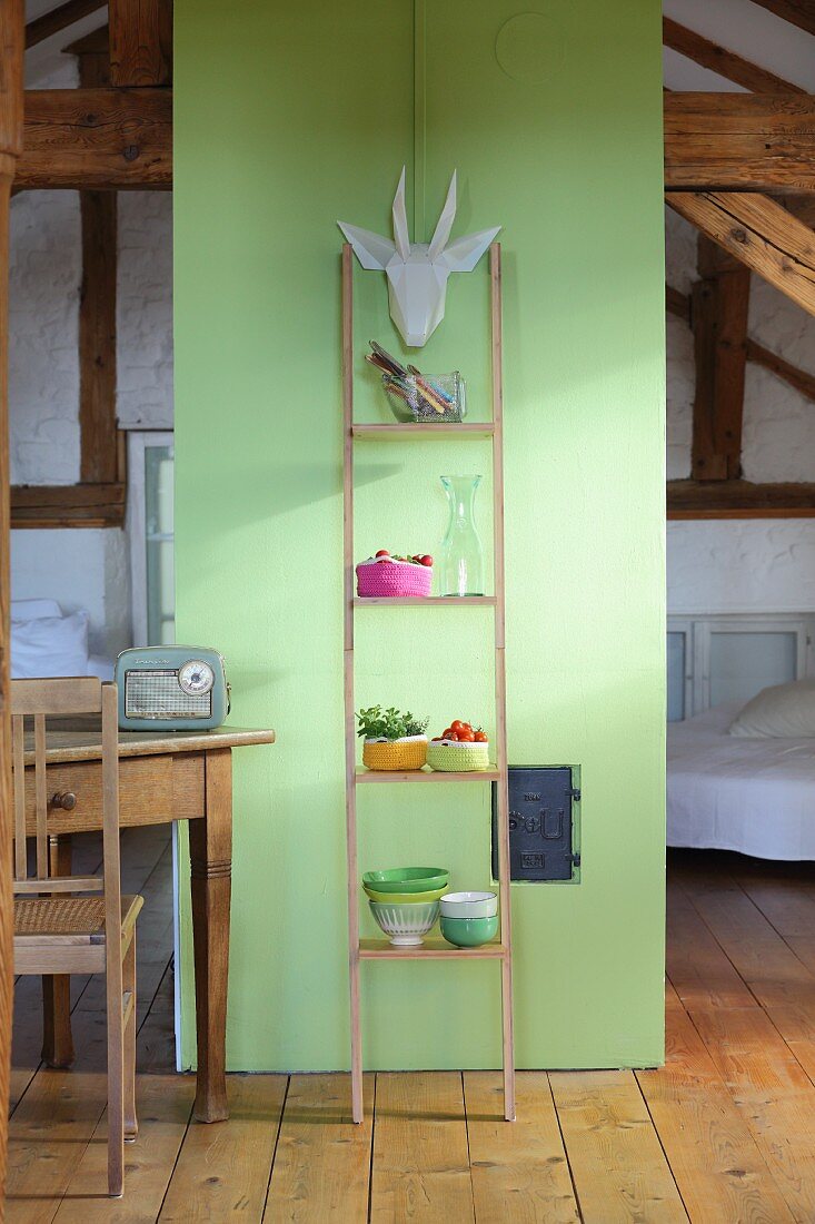 Ladder shelves leaning against green partition in attic room