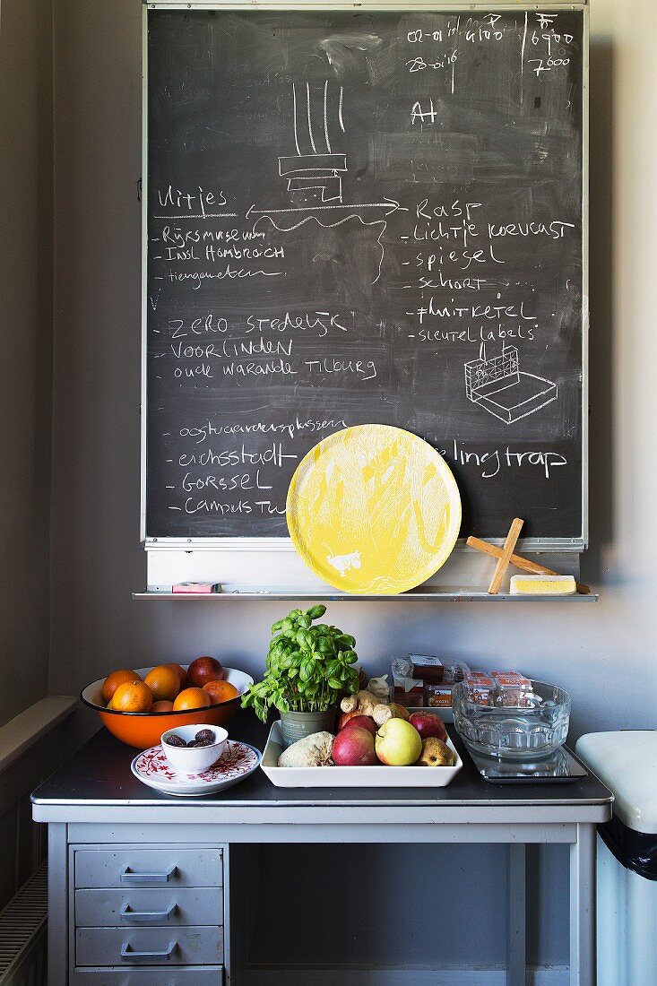Chalkboard on wall above fruit and vegetables on old workbench in kitchen