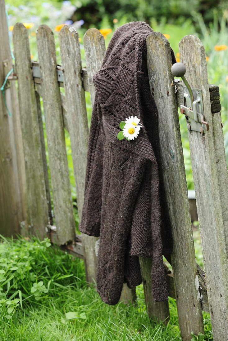 Flowers pinned to cardigan hung from vintage garden gate
