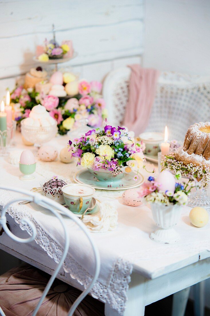 Romantisch gedeckter Ostertisch mit zarten Blüten und Kerzenlicht