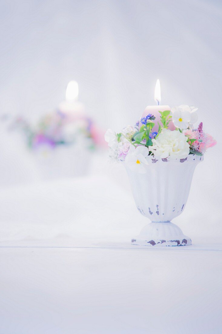 Romantisches Blumengesteck mit brennender Kerze vor Spiegel