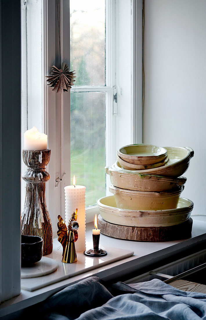 Lit candles and stacked bowls on windowsill