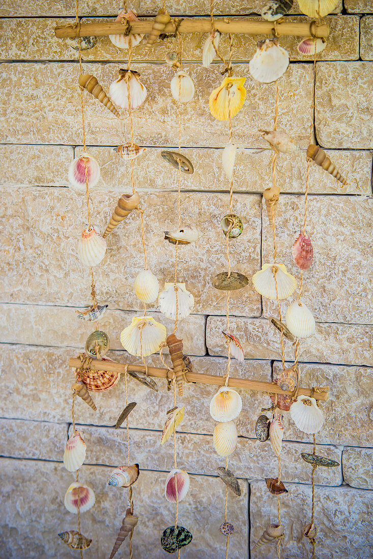Mobile made of shells in front of stone wall