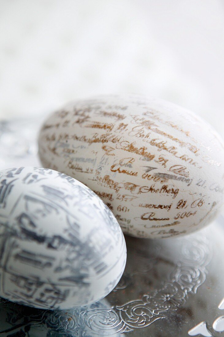 Two eggs printed with lettering and characters on engraved silver plate
