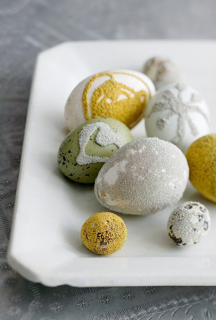 Verschiedene Eier mit Liebesperlen verziert auf weißer Porzellanplatte