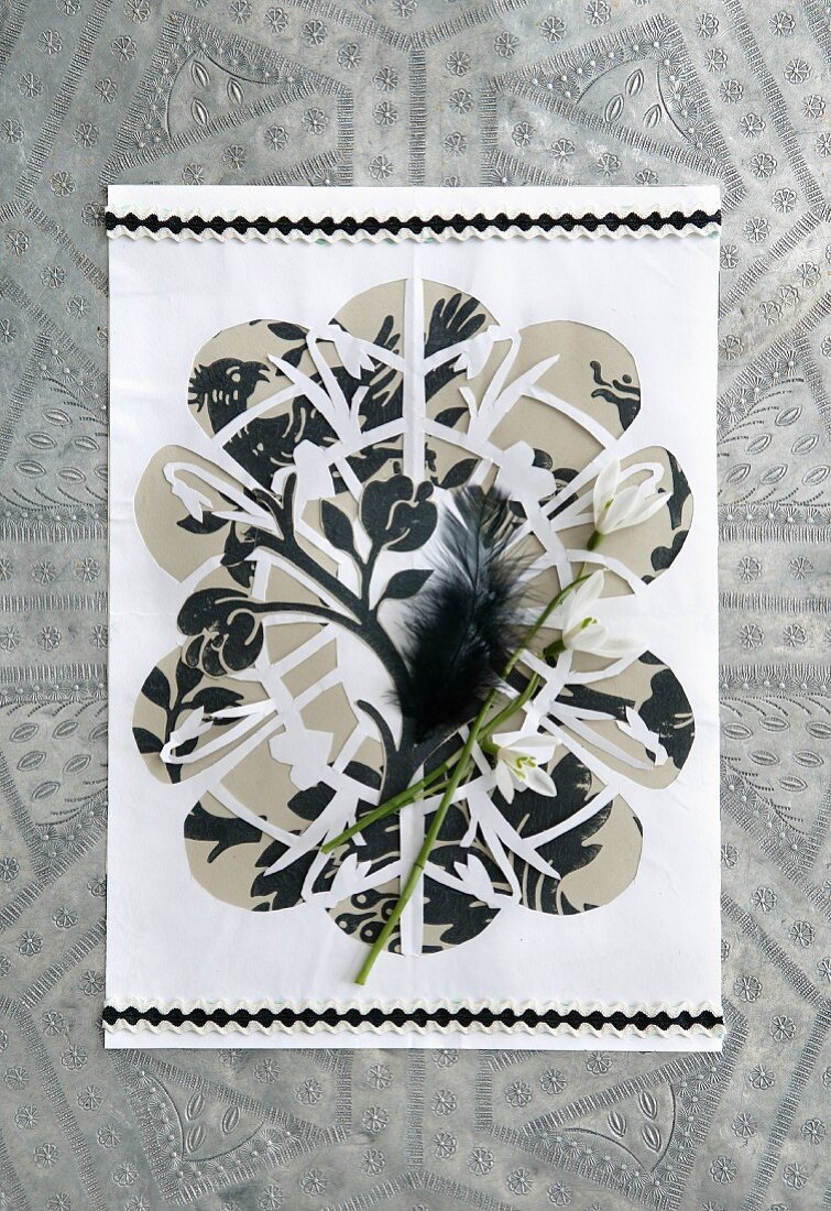 Papierkunst mit Schneeglöckchen und schwarzer Feder dekoriert